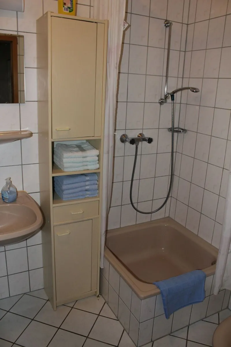 Bad mit Dusche und Regal mit Handtüchern