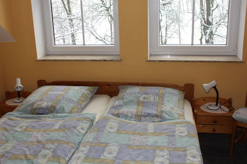 Schlafzimmer mit Doppelbett unter zwei Fenstern
