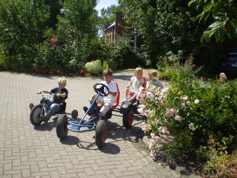 Kinder fahren mit Gokarts über den gepflasterten Hofplatz