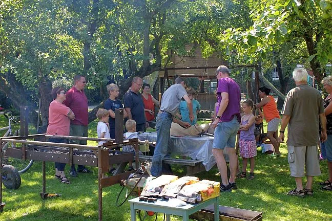 Grillabend im Garten mit Gästen am Grill und Tischen