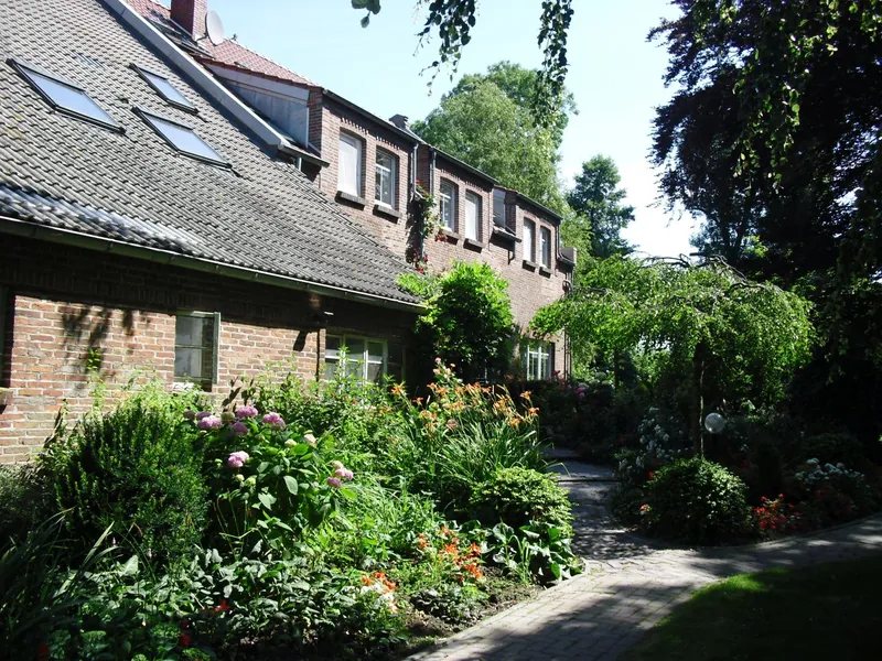 Das Gulfhaus aus rotem Klinker mit Gauben, davor der Garten
