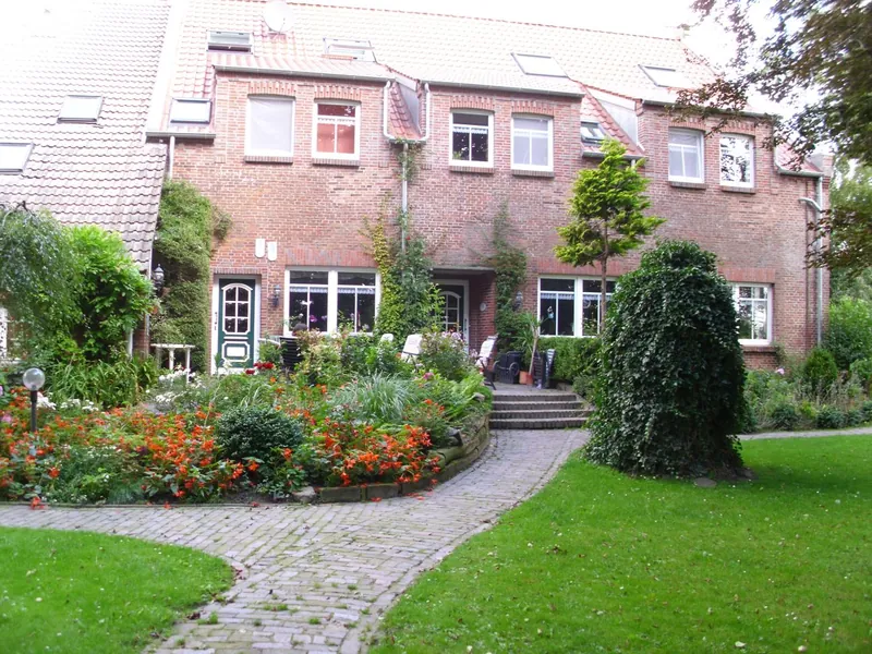 Südseite des Haupthauses mit Terrasse, Stufen, Blumenbeeten und Klinkerweg
