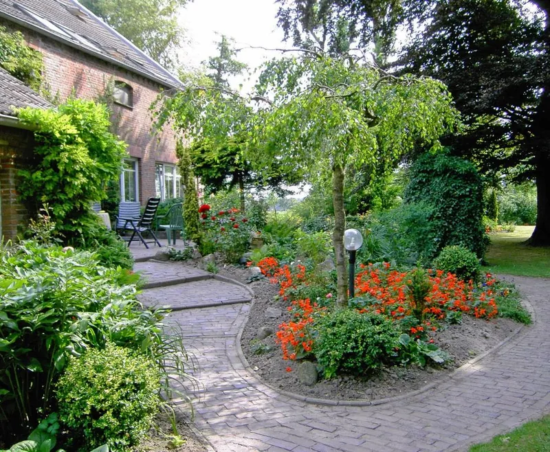 Gepflasterter Weg mit Blumenbeet und Laterne am Haupthaus