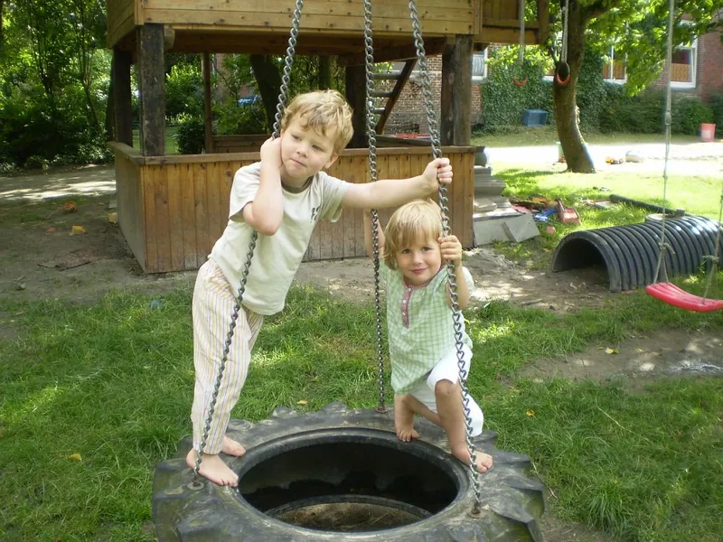 Zwei kleine Kinder spielen an der Reifenschaukel