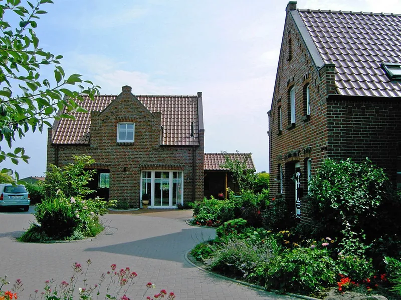 Zufahrt zum Gästehaus mit gepflasterter Umfahrung und Blumenbeeten