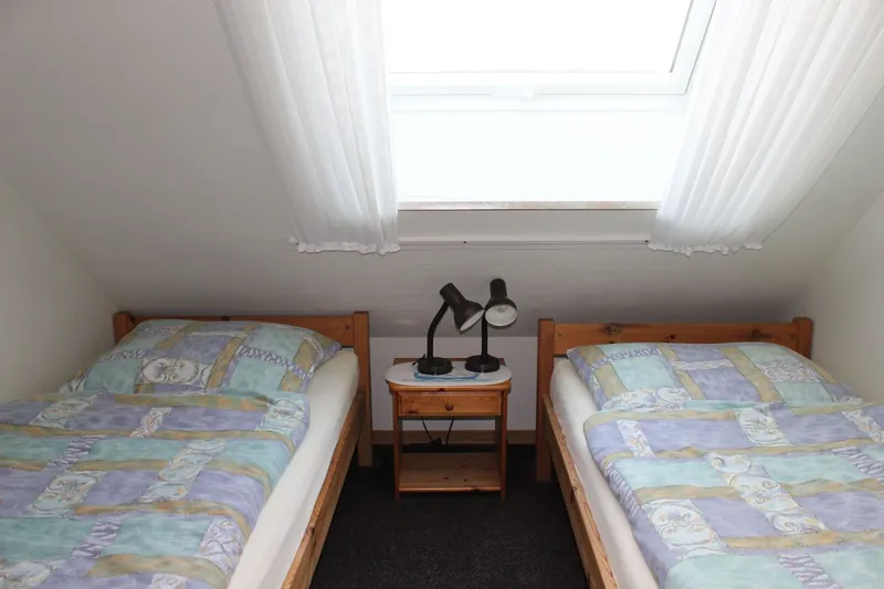 Kinderzimmer mit zwei Einzelbetten unter einem großen Dachfenster