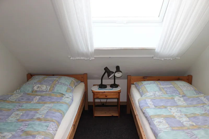 Kinderzimmer mit zwei Einzelbetten unter einem großen Dachfenster