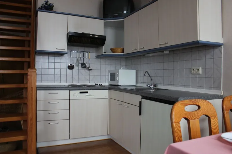 Einbauküche mit Herd und Spülmaschine neben der Treppe