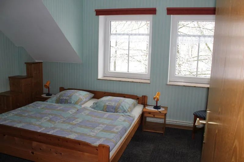 Schlafzimmer mit Doppelbett unter zwei Fenstern